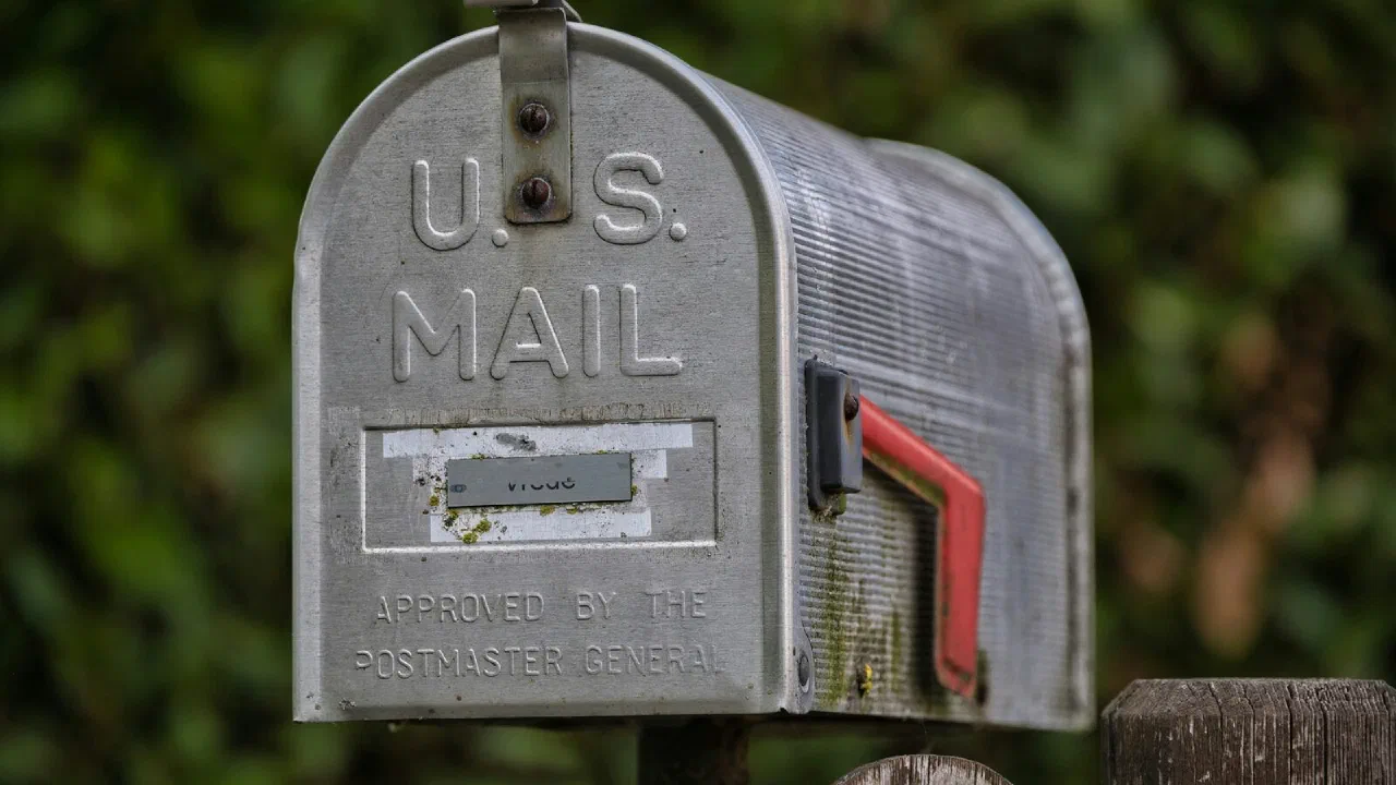 A weathered metal mailbox with its red flag raised