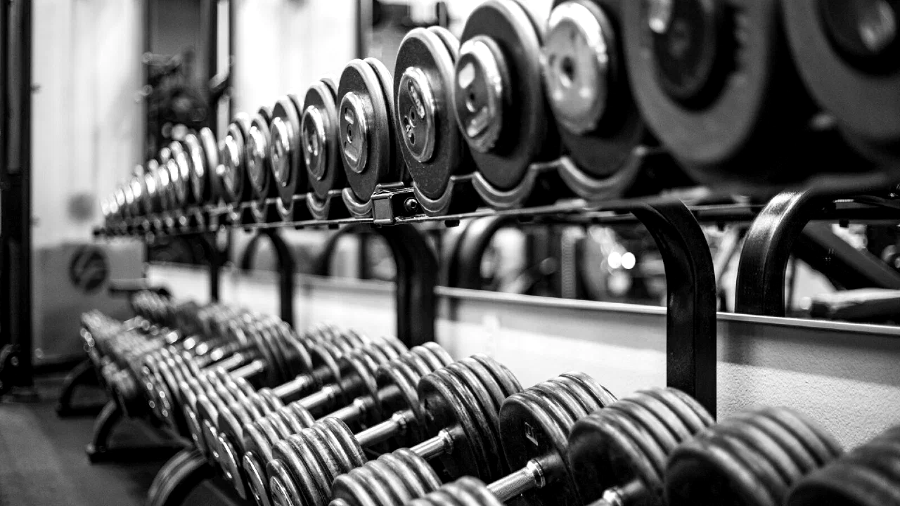 Pairs of dumbbells racked in a row, in black and white