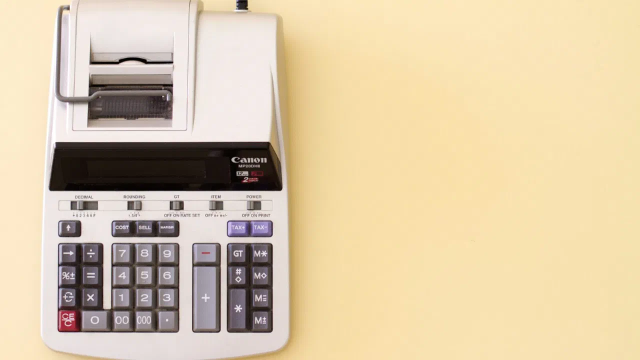 A grey printing calculator on a pale yellow background